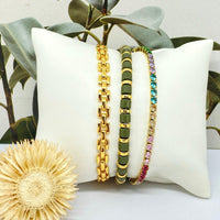 Conjunto de três pulseiras GRINE em aço inoxidável dourado, com pedras de strass coloridas e detalhes em verde.