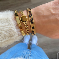 Conjunto de três pulseiras douradas GRINE em aço inoxidável, incluindo uma com pedra central e padrão animal print.