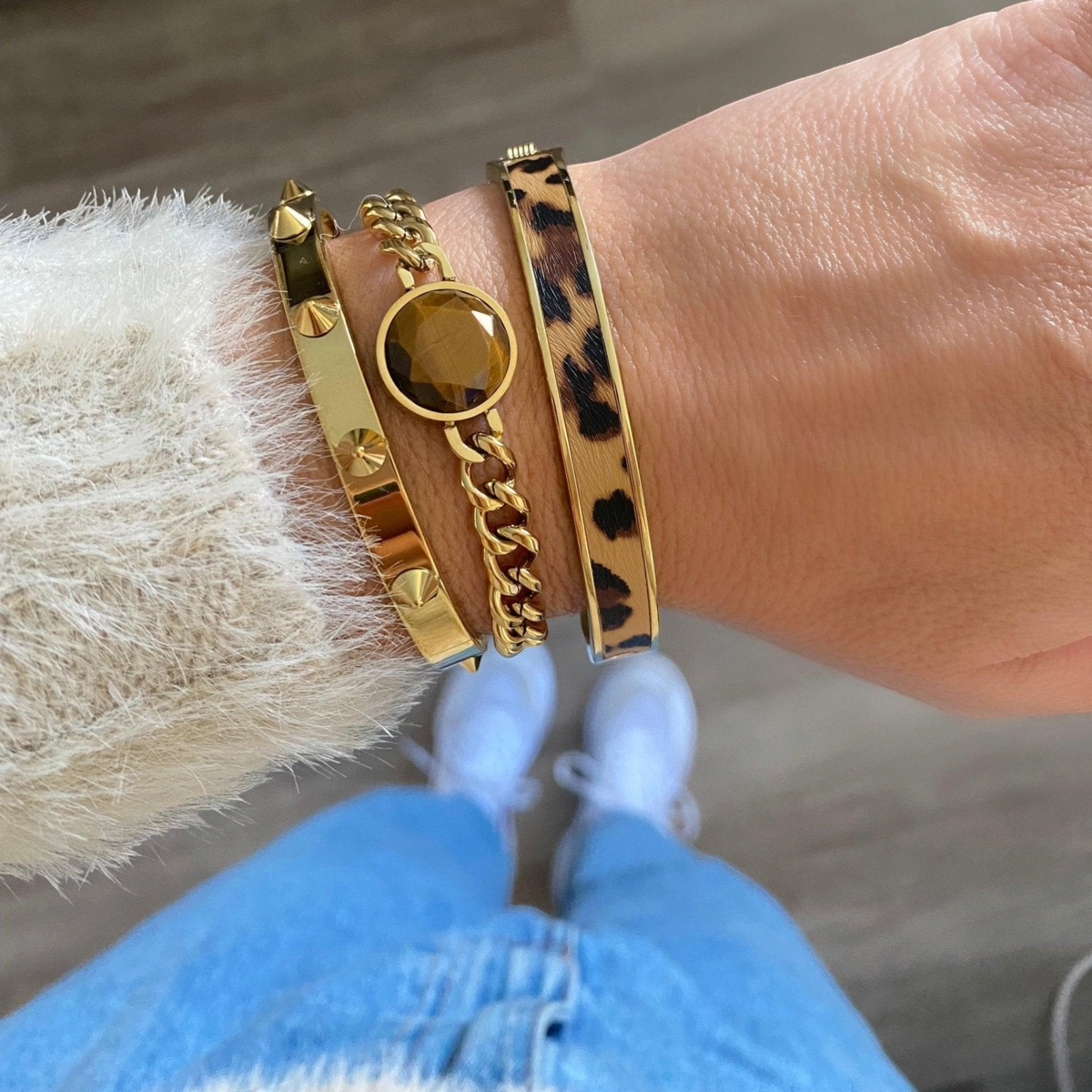 Conjunto de três pulseiras douradas GRINE em aço inoxidável, incluindo uma com pedra central e padrão animal print.