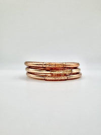 Conjunto de três pulseiras GRINE artesanais em tom dourado com folha de ouro e conector de cobre com mantra gravado