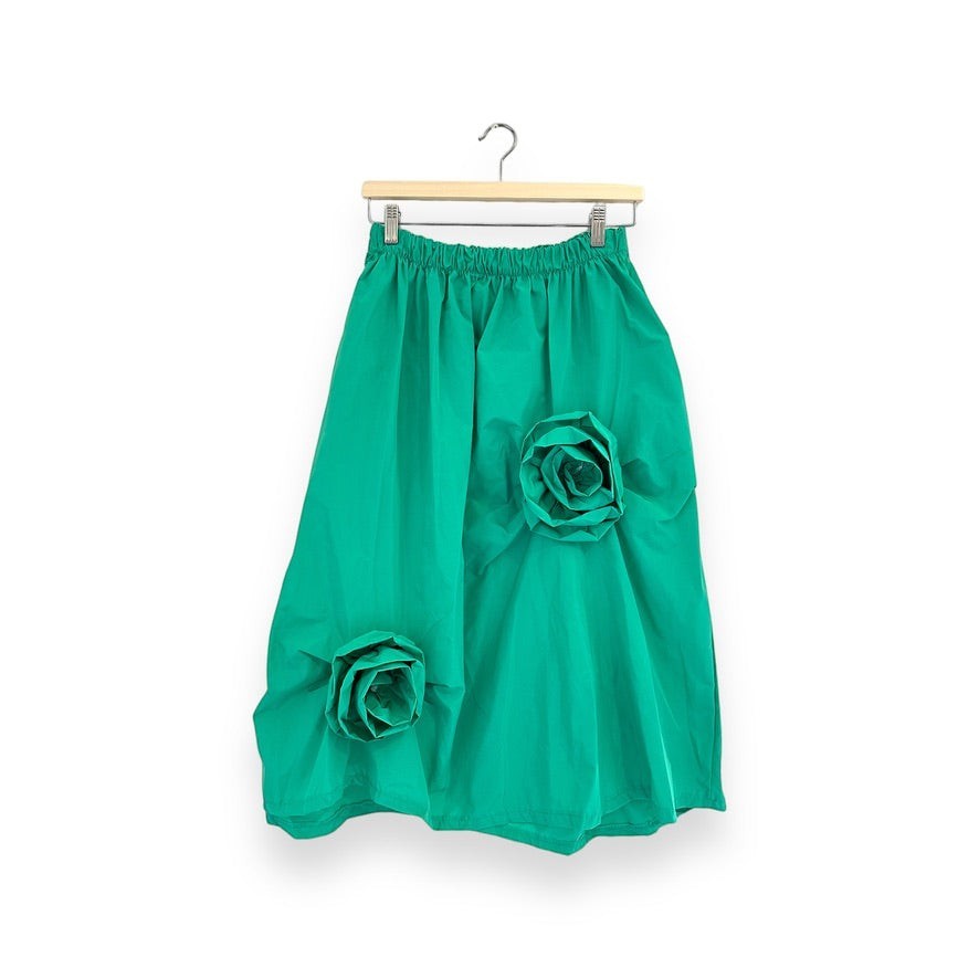 Saia midi GRINE verde esmeralda em tecido técnico estruturado com apliques de flores 3D em destaque.
