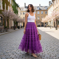 Mulher a usar saia comprida de tule roxo com folhos da GRINE, combinada com top branco numa rua calcetada.