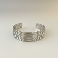 GRINE silver stainless steel cuff bracelet with a layered, open design. Adjustable and water-resistant.