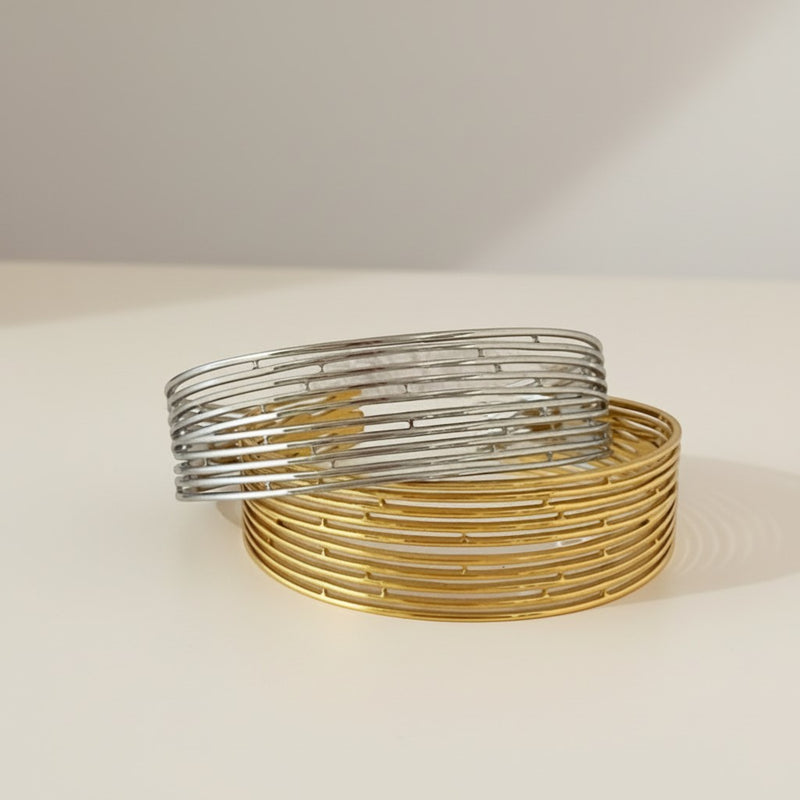 GRINE stackable stainless steel bangles, one silver, one gold, with a modern, open-link design.