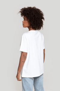 T-shirt branca de algodão GRINE com gola redonda e corte largo, vista de costas numa modelo com cabelo encaracolado.