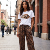 Modelo veste t-shirt branca GRINE de algodão com estampado de lábios em animal print e brilhantes na rua