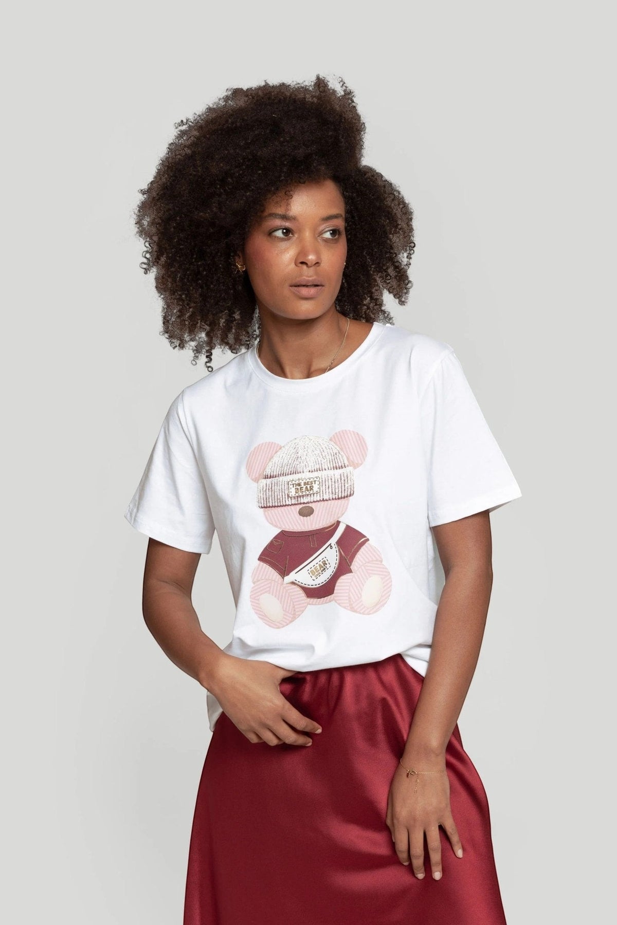 Modelo veste t-shirt branca GRINE de algodão com estampado gráfico de urso rosa e gola redonda