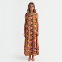 Modelo veste vestido GRINE comprido de algodão com padrão multicolorido de limões, laranjas e flores, corte fluido.