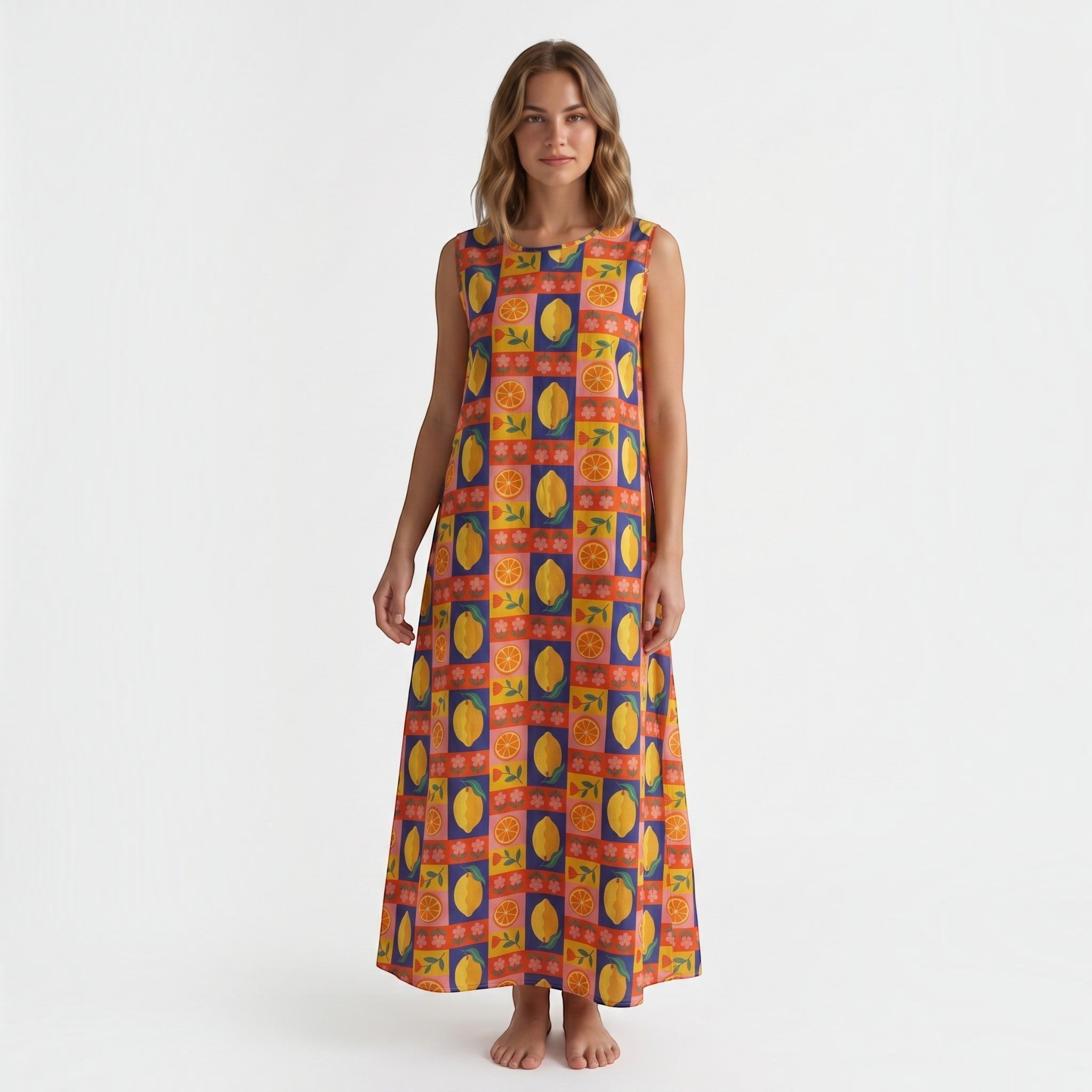Modelo veste vestido comprido GRINE em algodão com padrão multicolorido de laranjas, limões e flores, corte fluido.