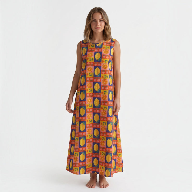 Modelo veste vestido comprido GRINE em algodão com padrão multicolorido de laranjas, limões e flores, corte fluido.