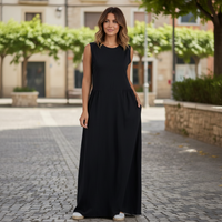 Modelo veste vestido comprido preto GRINE em algodão com corte evasê, decote redondo e sem mangas em ambiente urbano.