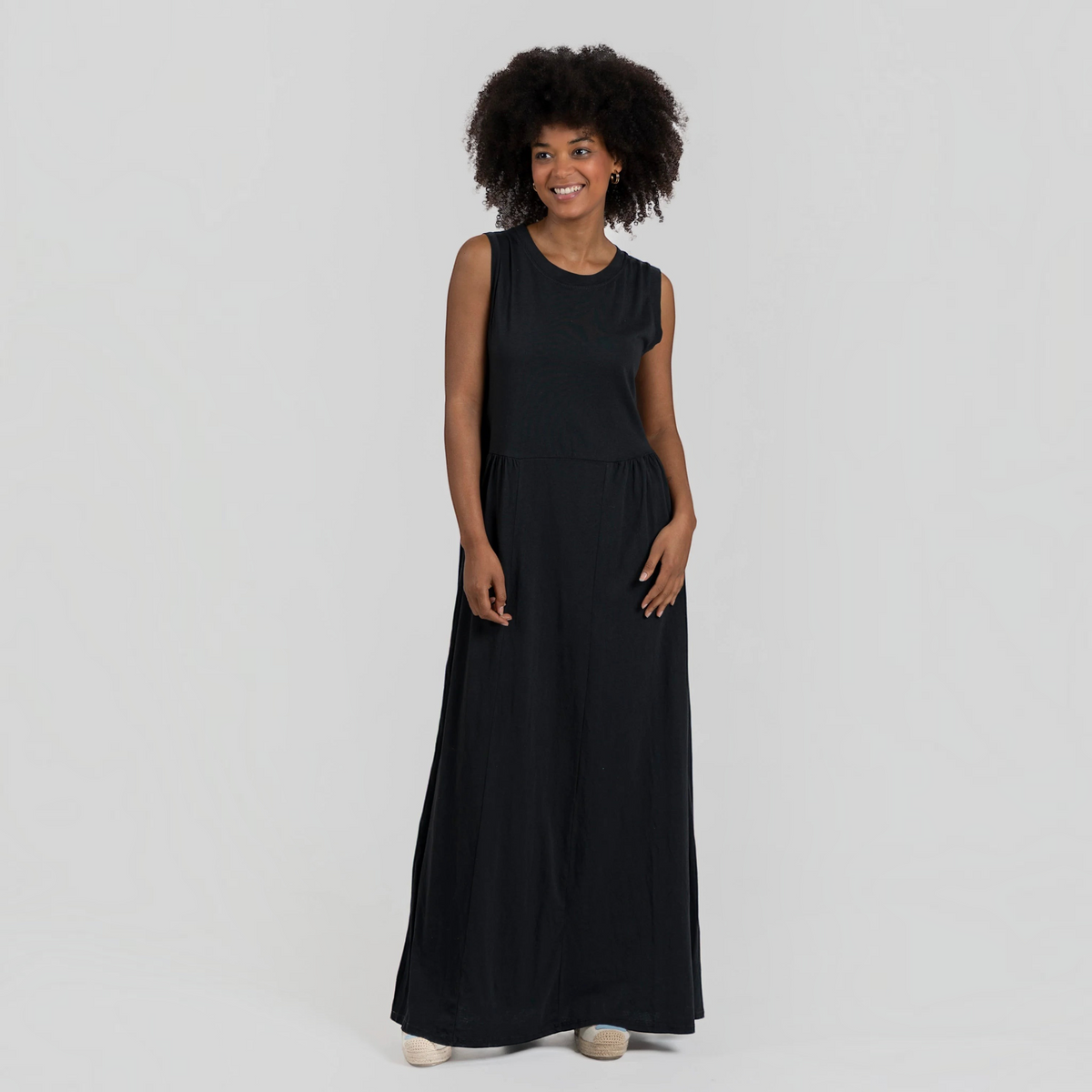 Modelo sorridente veste vestido comprido GRINE preto de algodão com corte evasê, decote redondo e sem mangas.