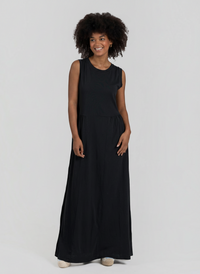 Modelo sorridente veste vestido comprido preto GRINE em algodão com corte evasê, decote redondo e sem mangas