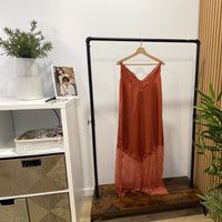 Vestido comprido GRINE cor ferrugem com alças finas, decote em V e detalhes delicados em renda na base e no peito.