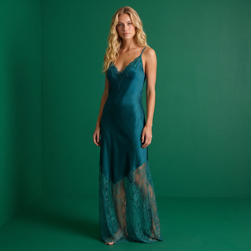 Modelo loira veste vestido comprido GRINE em tom verde-petróleo com detalhes em renda no decote e na bainha