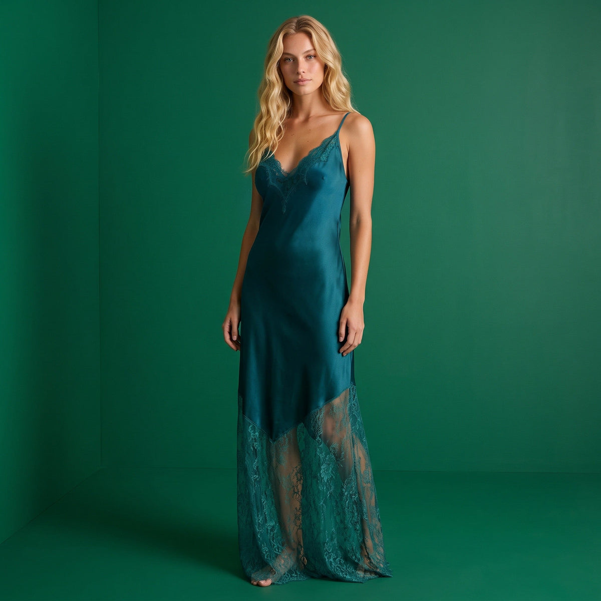 Modelo loira veste vestido comprido GRINE verde-petróleo com alças finas e detalhes em renda no decote e na bainha.