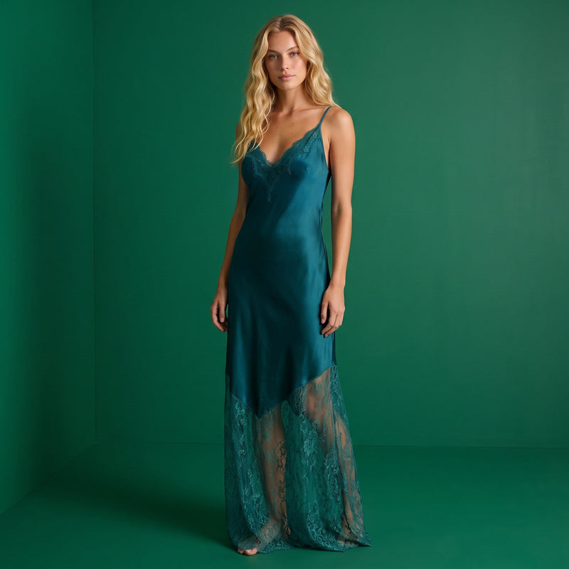 Modelo loira veste vestido comprido GRINE verde-petróleo com alças finas e detalhes em renda no decote e na bainha.