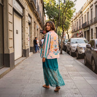Modelo GRINE veste vestido comprido verde com detalhes em renda na base, combinado com casaco estampado na rua.