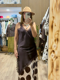 Mulher a usar vestido curto acetinado GRINE castanho com decote em V, detalhes em renda e padrão de bolas na bainha