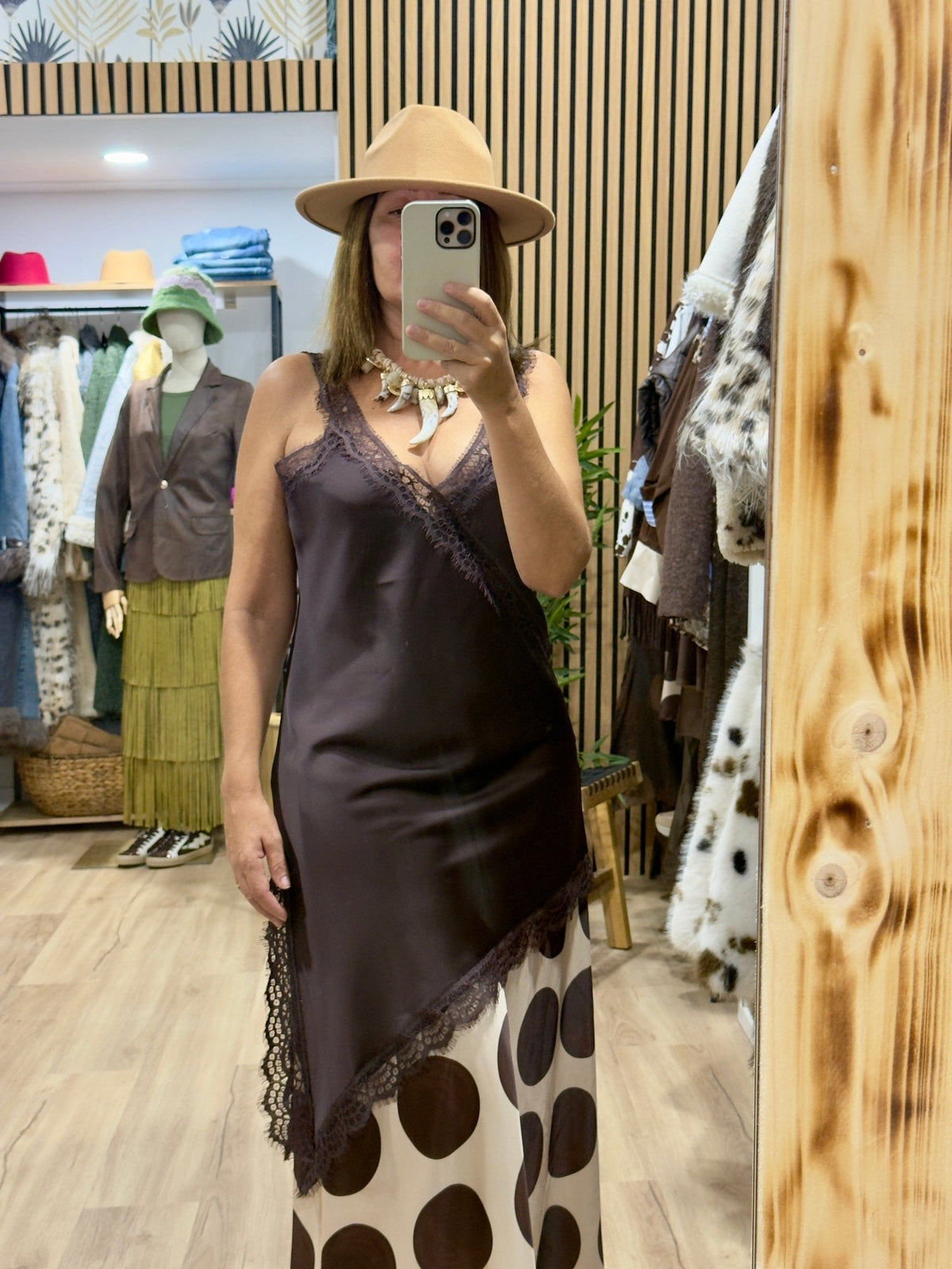 Mulher a usar vestido curto acetinado GRINE castanho com decote em V, detalhes em renda e padrão de bolas na bainha