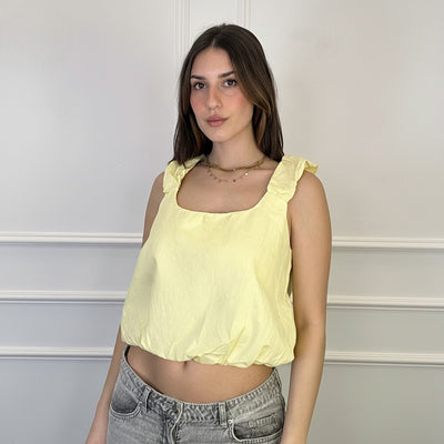 GRINE yellow cotton square neck cropped top with ruffled cap sleeves and elasticated hem. Model wears grey jeans.