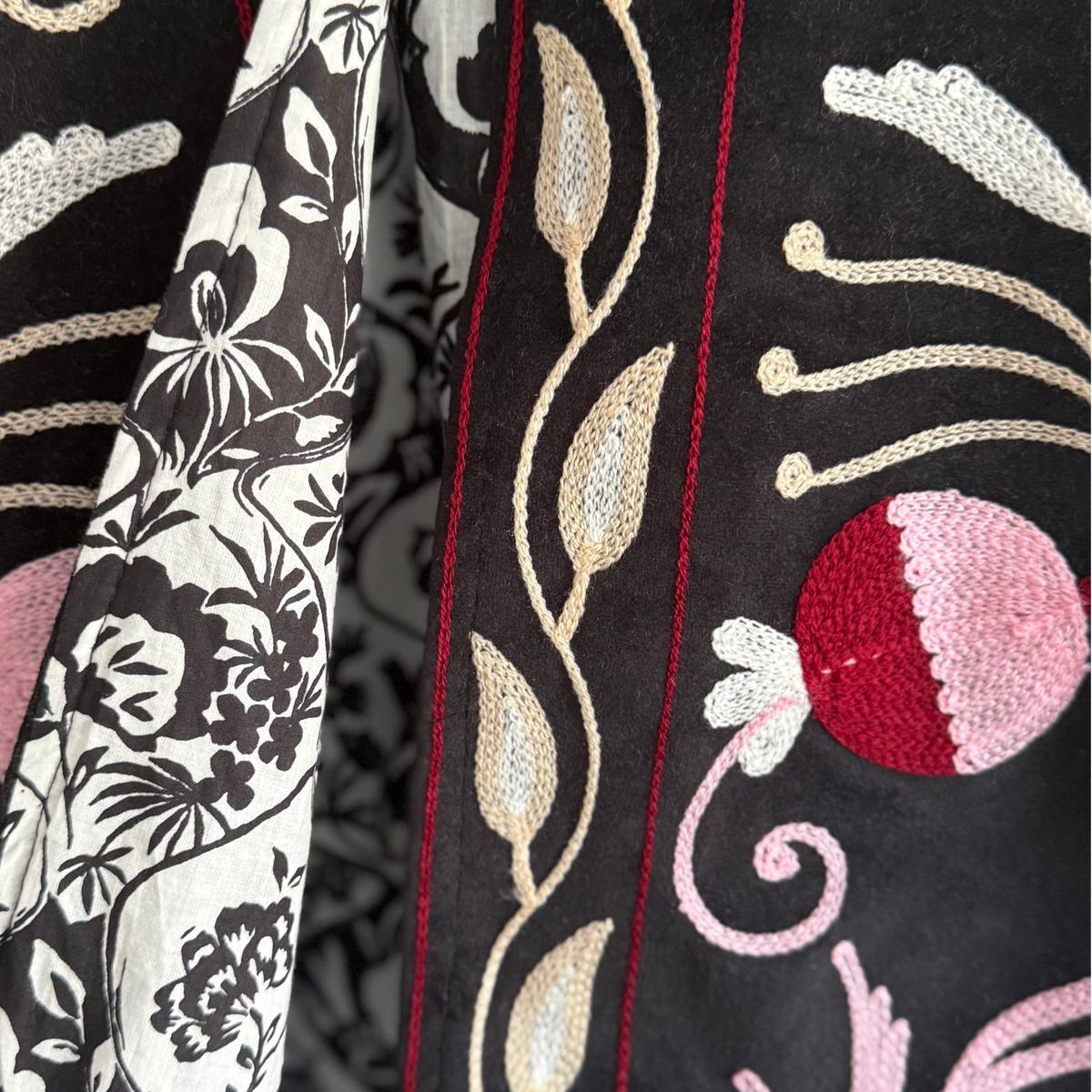 Detalhe de casaco Grine em veludo preto com bordados florais coloridos e interior em algodão estampado blockprint.
